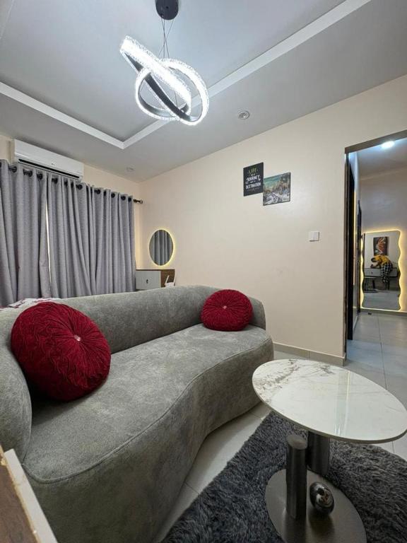 a living room with a gray couch and red pillows at Pinecourt Luxury Apartment in Ikate