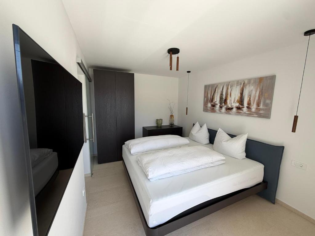 a bedroom with a white bed and a television at Villa Čapula - Modern Apartment with Sea View and Parking, Marušići in Omiš