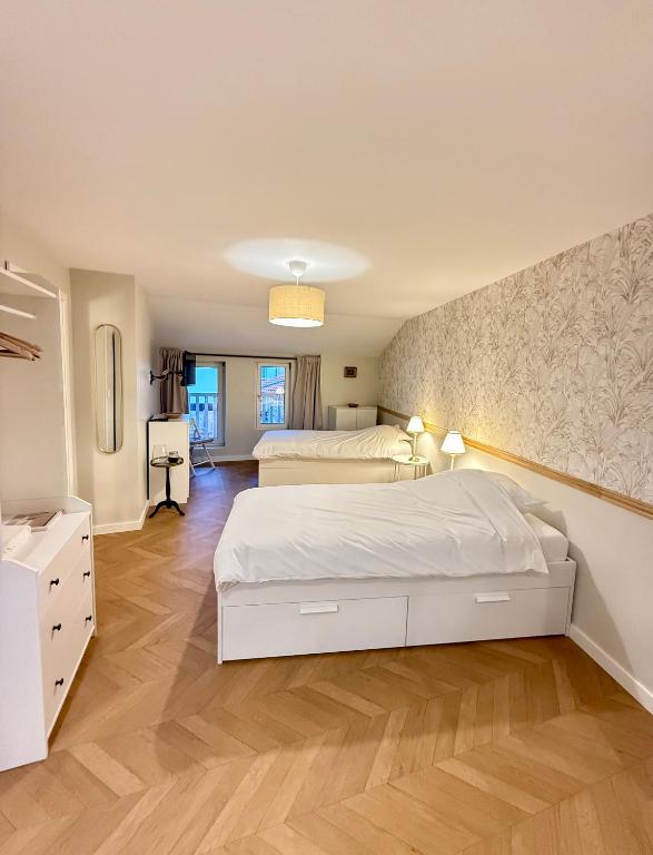 a large bedroom with two beds and a wooden floor at La petite maison orange in Koenigsmacker