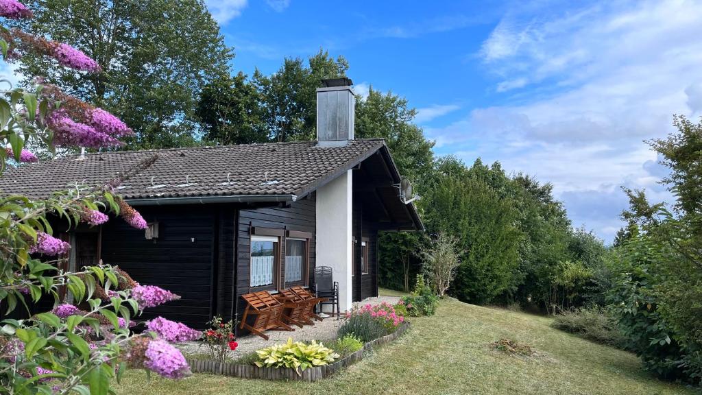 a small cottage with a bench and flowers at Ferienhaus Waldliebe in Grafenau