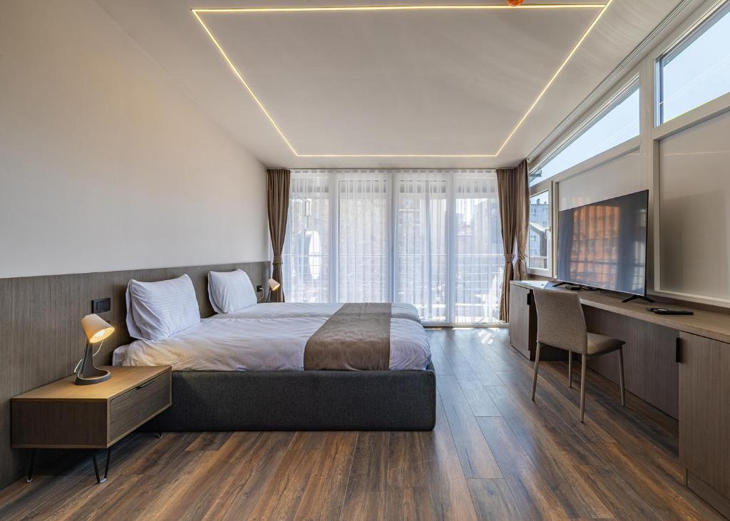 a bedroom with a bed and a desk and a television at Four Side Hotel in Prishtinë