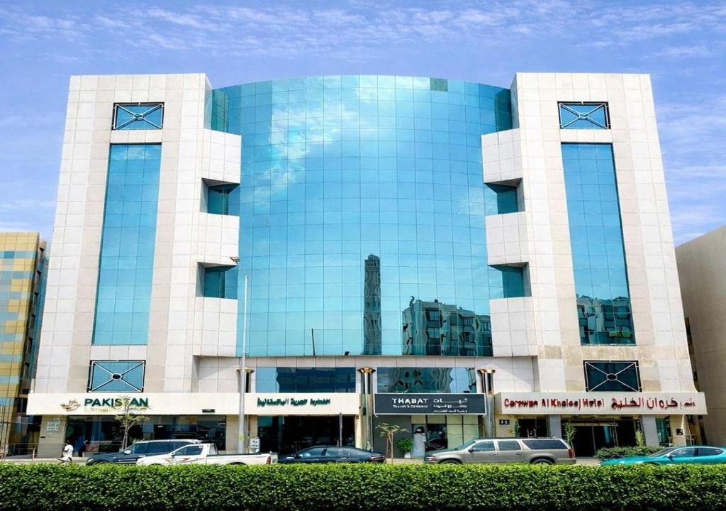 a large glass building with cars parked in front of it at Carawan Al Khaleej Hotel Olaya in Riyadh