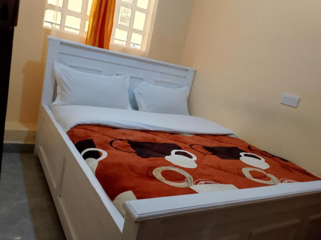 a white bed with a cow blanket on it at Mwembe Airbnbs in Kisii