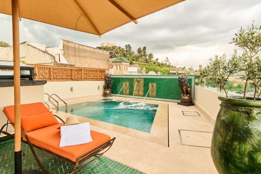 a pool on the roof of a house with an umbrella at Riad May Fes Original & Spa in Fez