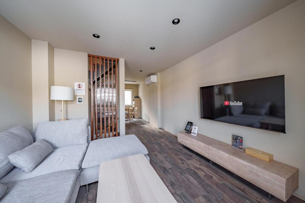 a living room with a couch and a large flat screen tv at ZABOCON Honcho Terrace in Sapporo