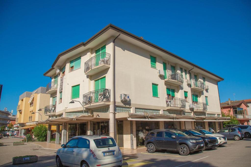 a large building with cars parked in a parking lot at Downtown apartment by the beach in Eraclea Mare