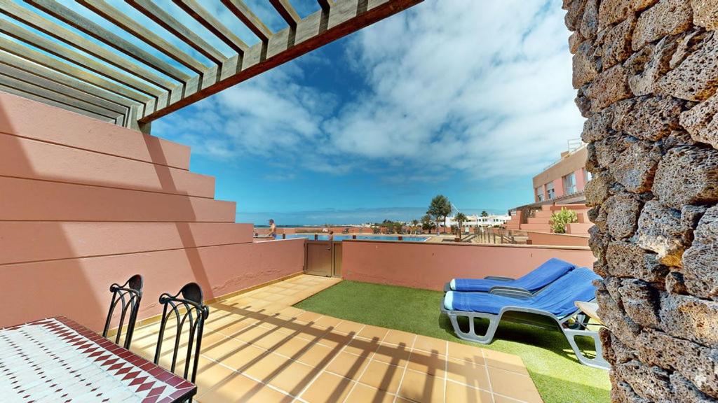 a patio with two blue chairs and a wall at Beach Apartment Marfolin 06 El Cotillo in El Cotillo