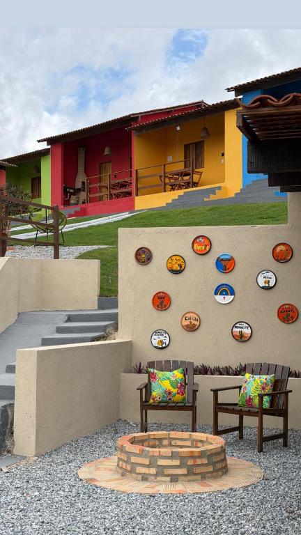 a building with two chairs and a wall with plates on it at Casa Laranja Recanto Doce Lar in Gravatá