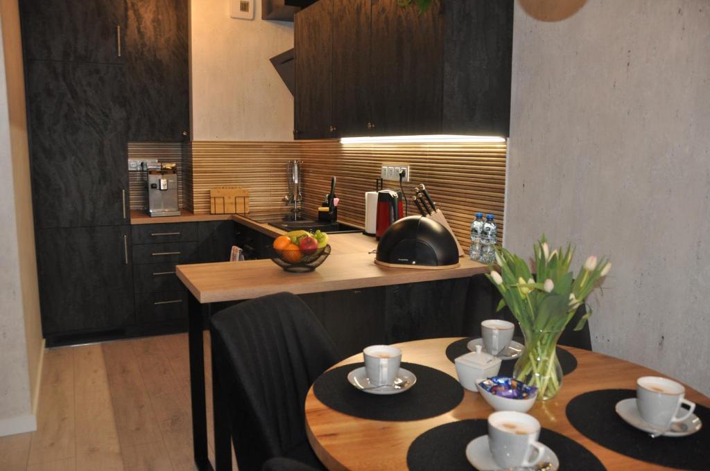 a kitchen with two tables with cups and plates on it at Apartament SANOVA 55 in Sanok