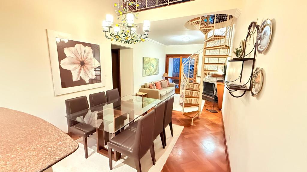 a dining room and living room with a table and chairs at Espaçoso Apto triplo a 300 mts do Centrinho Capivari in Campos do Jordão