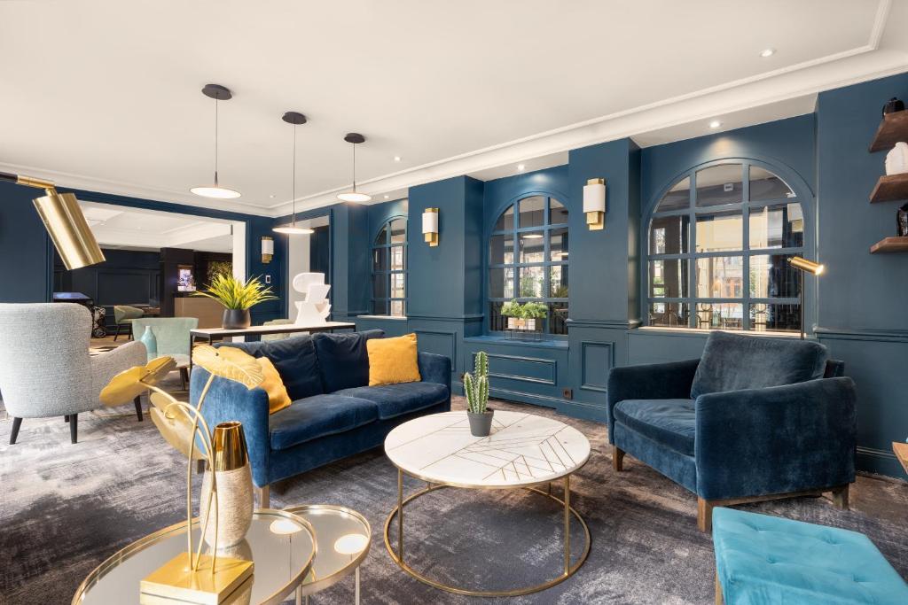 a living room with blue walls and blue furniture at Hôtel le Royal Rive Gauche in Paris