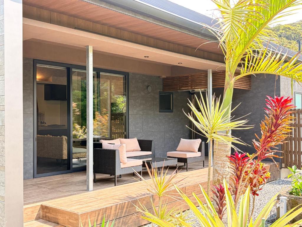 a patio with two chairs and a table at 奄美 Palm Tree Terrace in Ōkachi