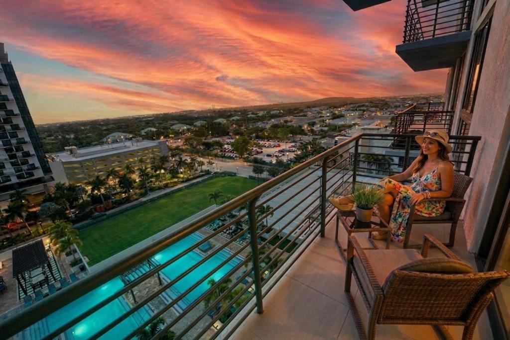 a woman sitting on a balcony with a view of a city at Modern Studio Pool View Downtown Doral' Heart in Miami
