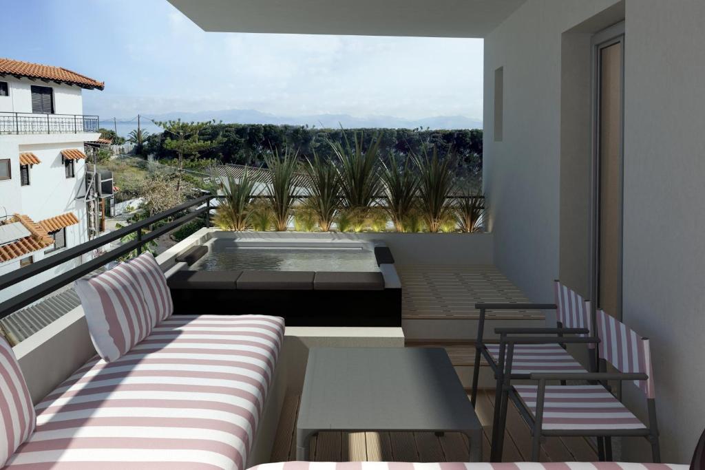 a balcony with a pool and chairs and a table at Aktaion Signature Suites in Skala