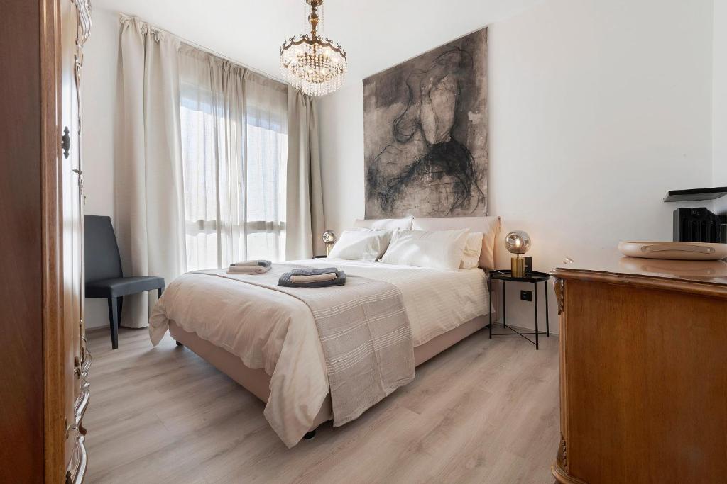 a white bedroom with a bed and a chandelier at Lake Como Style Home in Lecco