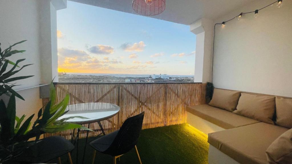 a balcony with a couch and a table and a window at Sunset Dream Suite El Cotillo in El Cotillo
