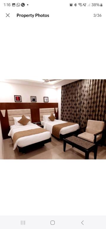 two beds in a room with two chairs at New KR Inn in Jadgenhalli