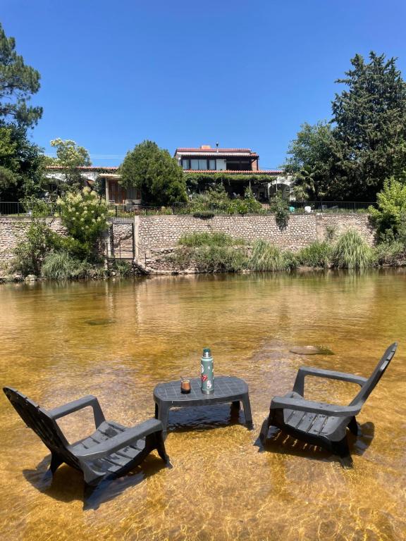 two chairs and a table in the middle of a river at Cabañas el Bierzo in Villa Cura Brochero