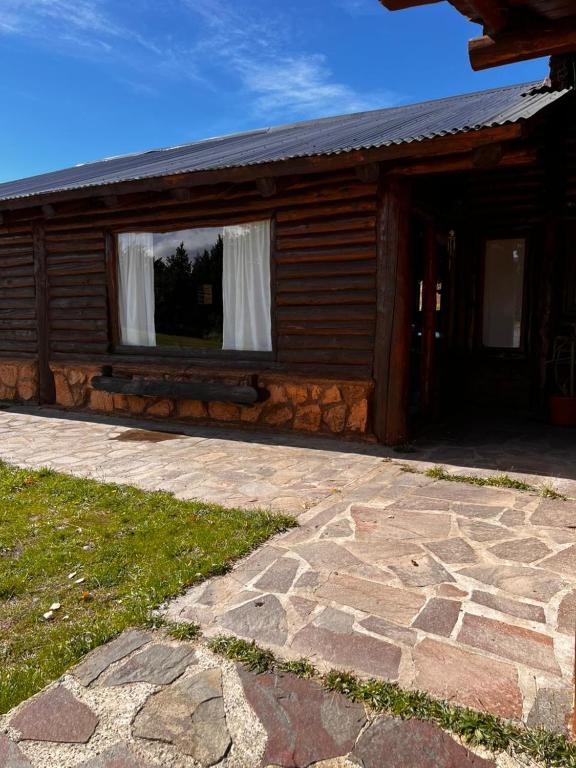 a log cabin with a window and a stone patio at cabaña Quovadis in Trevelín