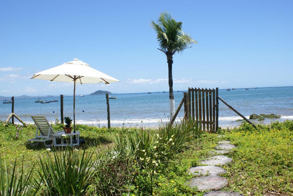 a beach with a chair and an umbrella and a palm tree at recanto do paraiso in Penha