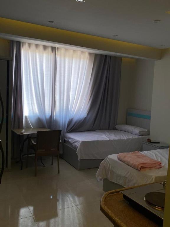 a bedroom with two beds and a desk and a window at Egy property in 6th Of October