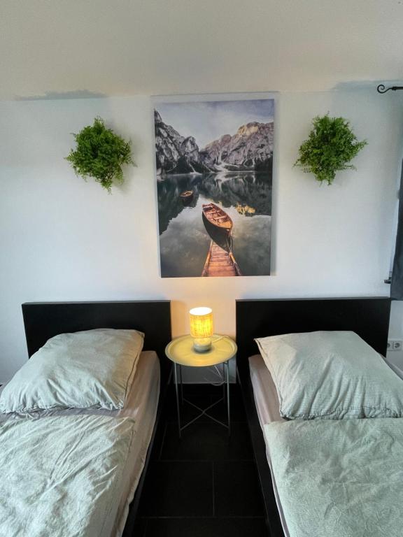a room with two beds and a table with a picture on the wall at Fuldablick in Melsungen