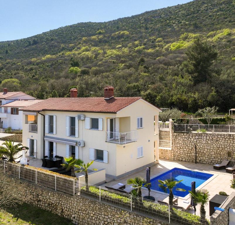 a villa with a swimming pool and a mountain at Apartment Paradiso - Ravni in Labin