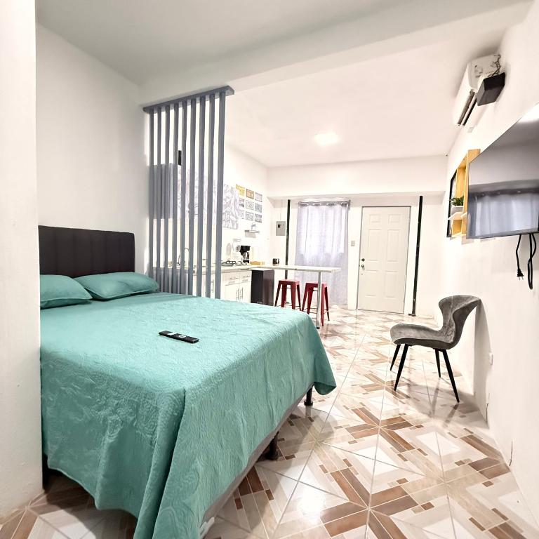 a bedroom with a green bed and a kitchen at Apartamento Ulm in Flores