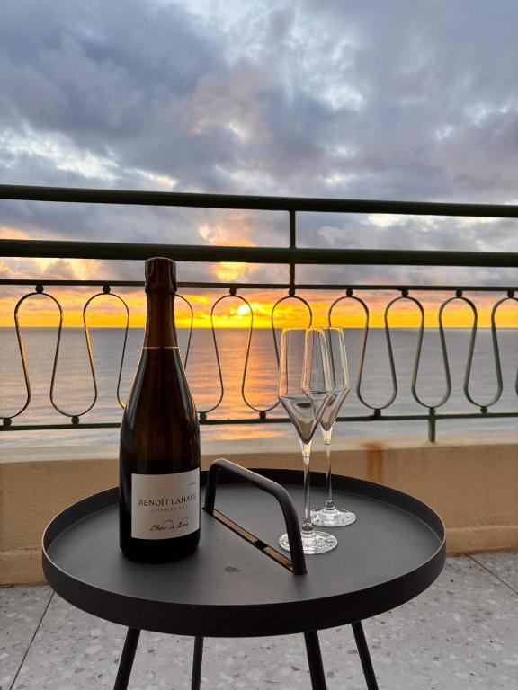 a bottle of wine and two glasses on a table at Un balcon sur la mer in Nice