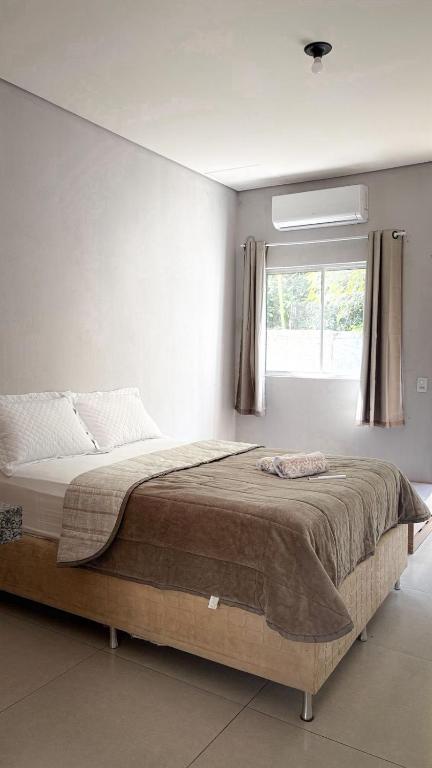 a bedroom with a large bed with a window at Fica Aki - Hospedagem Alta Floresta in Alta Floresta