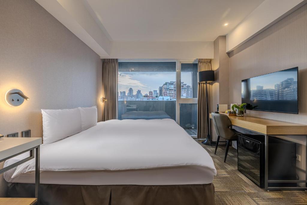 a hotel room with a bed and a desk and a window at Retro Taichung in Taichung