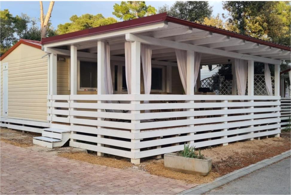 a house with a white fence in front of it at Mobilheim Coco in Biograd na Moru