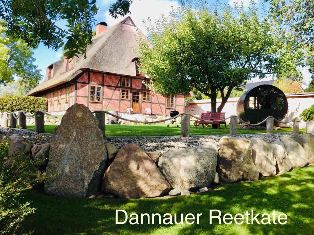 a house with a stone fence in front of a building at Dannauer Reetkate - Wiesenblick in Oldenburg in Holstein