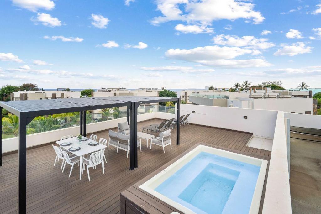 a balcony with a table and a swimming pool at Penthouse Kyo - Private Rooftop & Jacuzzi in Grand-Baie