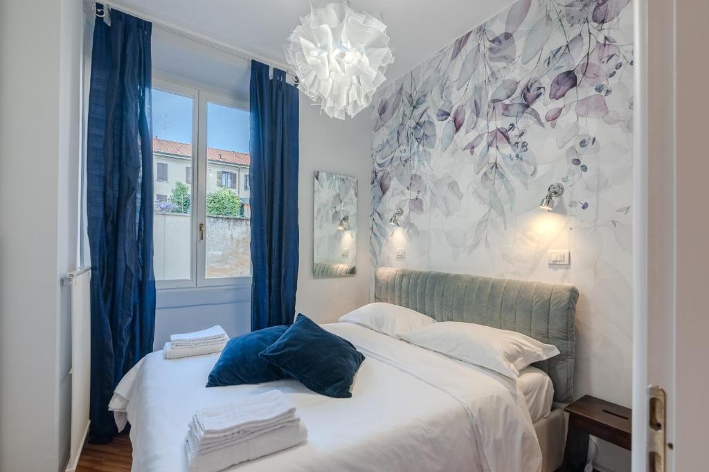 a bedroom with two beds with blue curtains and a chandelier at BM7-Design&Style in Milan