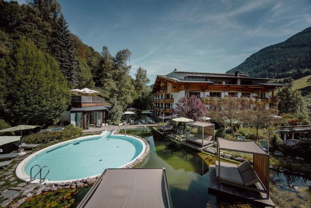 a resort with a swimming pool and a building at Familien- & Gartenhotel Theresia 4-Sterne Superior in Saalbach-Hinterglemm