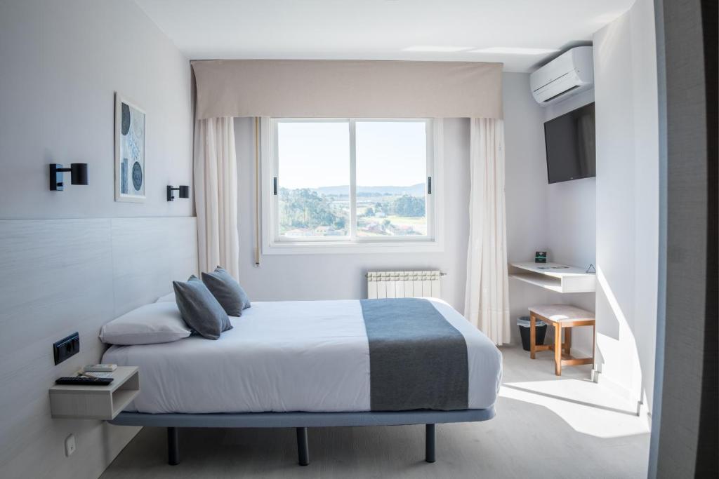 ein Schlafzimmer mit einem großen Bett und einem Fenster in der Unterkunft Alda Arteixo in Vilarrodis