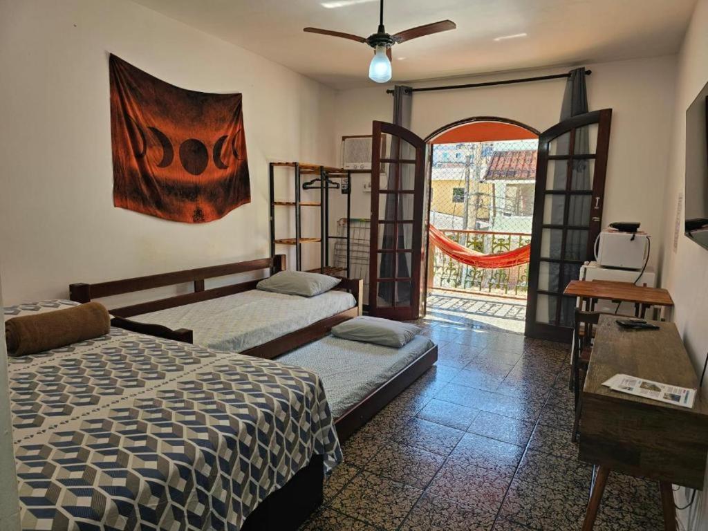 a bedroom with two beds and a large window at Suíte Rodoviária no centro de Arraial in Arraial do Cabo