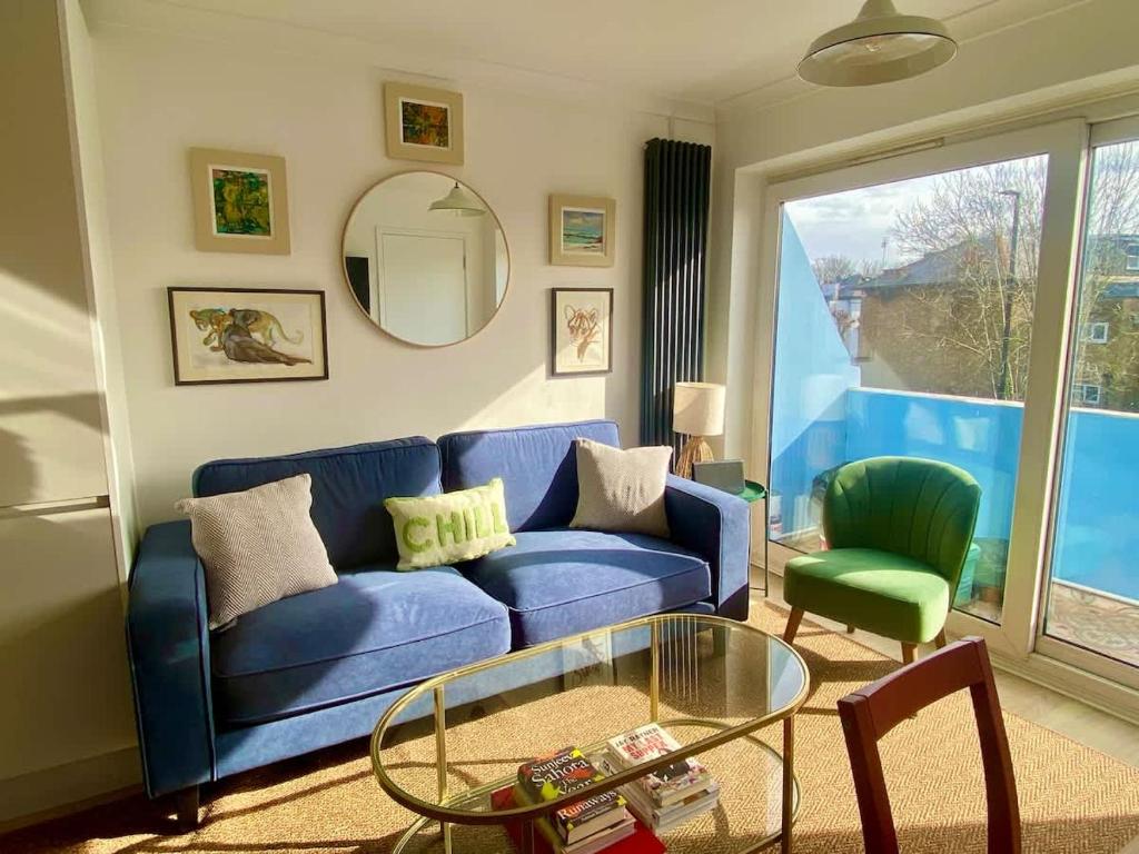 a living room with a blue couch and a glass table at Modern 2-Bed Apartment with Off-Street Parking in Chiswick in London