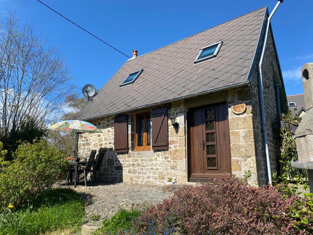 a small stone house with an umbrella in front of it at The Bakery in Beauficel