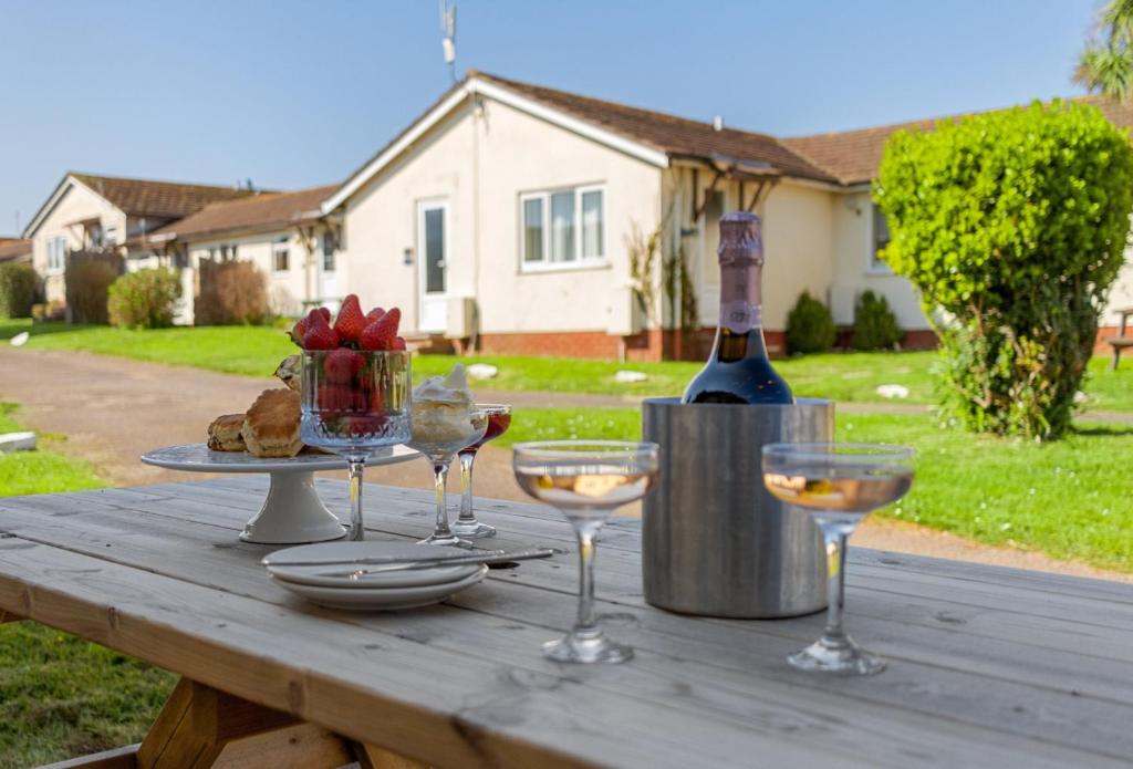 a wooden table with wine glasses and a bottle of wine at Landscove Chalet 23 in Brixham