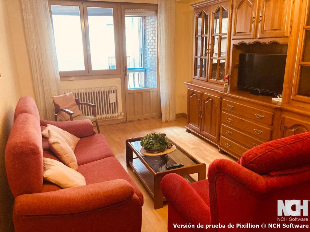 a living room with two red chairs and a tv at Amapola 1 in Soria