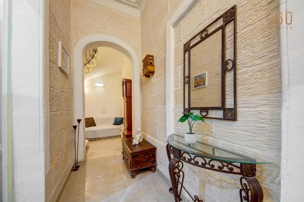 a hallway with a mirror and a glass table at Suite Victory Authentic Maltese Duplex in Birgu in Birgu