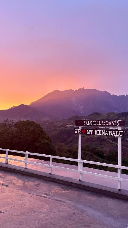 a sign on the side of a road with the mountains at Sanhill & Oasis in Ranau