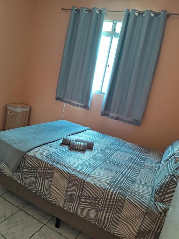 a bedroom with a bed with blue curtains at Apto inteiro 2 quartos Elvamar in Governador Valadares