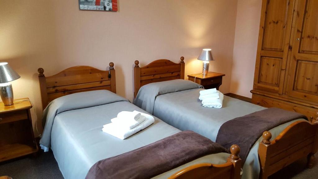 two twin beds in a room with two lamps at Hotel Calaluna in Biella