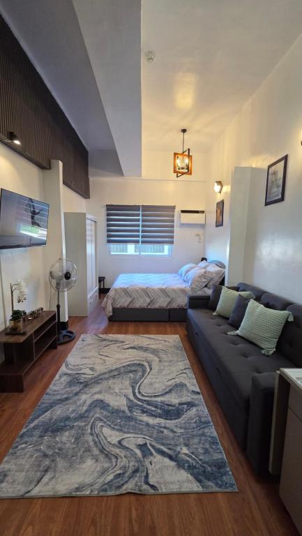 a living room with a couch and a bed and a rug at Kim's Cozy Place - Parthenon Residences in Cebu City