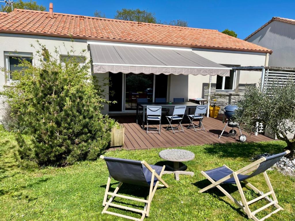 a house with a deck with chairs and a table at Le Relais du 49 - Gîte in La Séguinière