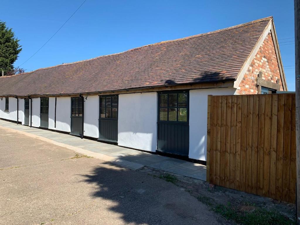 a white and black building with a wooden fence at 3 or 4 Bed 2 Bath Cosy Rural Barn Conversion-Parking in Beoley