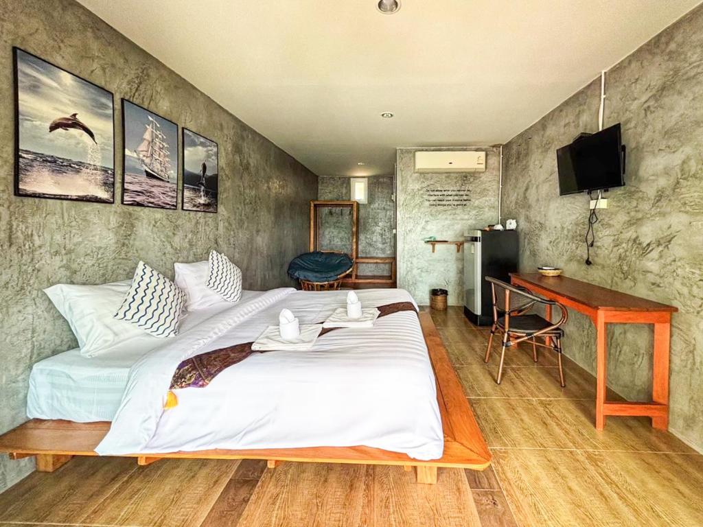 a bedroom with a large bed and a desk at Klang Aow Resort in Khanom